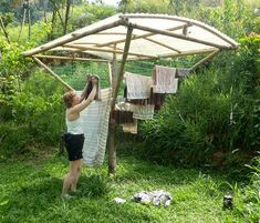 a woman is drying her clothes outside in the grass