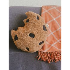 an orange and white throw sitting on top of a couch next to a decorative pillow