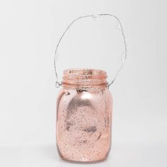 a pink glass jar with water pouring out of it and a handle on the top