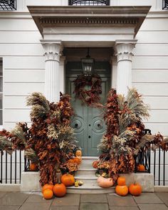 two pumpkins are sitting on the front steps of a house with wreaths around them