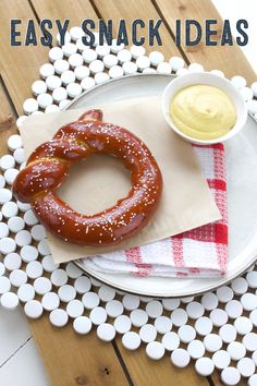 a pretzel sitting on top of a white plate next to a bowl of mustard