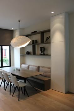 a dining room table and some chairs in front of a large window with open shelves