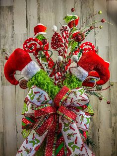 a christmas wreath with candy canes and santa hats on it, sitting in front of a wooden wall