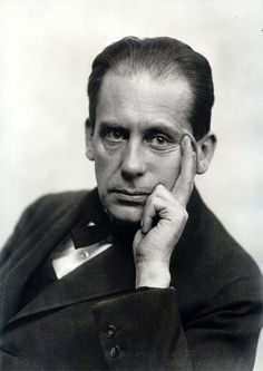 an old black and white photo of a man in a suit with his hand on his chin