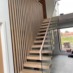 a wooden stair case with glass balustncing and wood handrails in a house