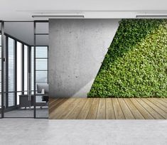 an empty room with a wall covered in green plants and a wooden floor that leads to the outside