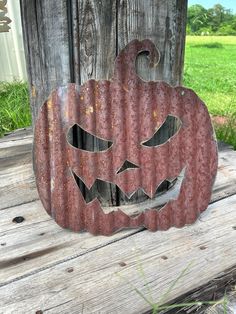 a metal pumpkin sitting on top of a wooden table next to a fence and grass