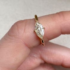 a person's hand holding a gold ring with a diamond on the top and bottom