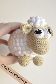 a hand holding a small crocheted sheep ornament