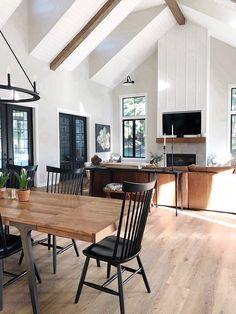 a large open concept kitchen and dining room with white walls, wood flooring and exposed beams