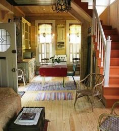 a living room filled with furniture and a stair case next to a table on top of a hard wood floor