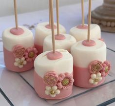 small cake pops decorated with pink and white flowers on a glass plate, ready to be eaten