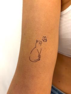 a woman's arm with a small tattoo of a cat and a butterfly on it