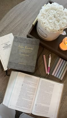 an open book sitting on top of a table next to a candle and some books