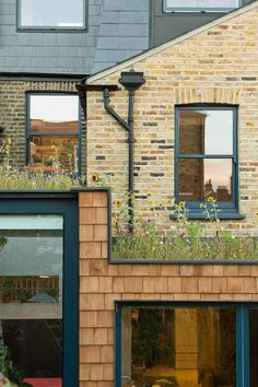 an apartment building with a green roof and flowers growing on the windows sills