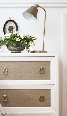 a white dresser with two drawers and a lamp