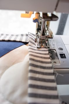 the sewing machine is working on the striped fabric that's being sewn together