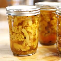 three jars filled with food sitting on top of a wooden table