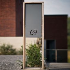 a tall wooden sign sitting on the side of a road next to a small tree