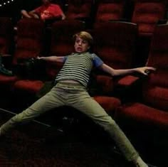 a man laying on the floor in front of red chairs with his arms stretched out