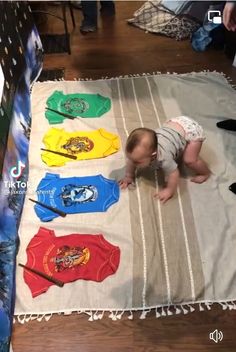 a baby laying on top of a rug covered in t - shirts