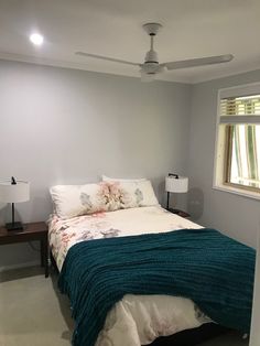 a bed sitting in a bedroom next to a window with blinds on the windowsill