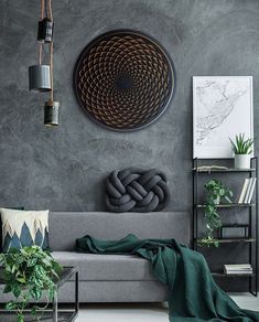 a living room with a gray couch, green throw pillows and a large circular artwork on the wall