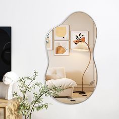 a living room scene with focus on the wall mirror and vase filled with plant life