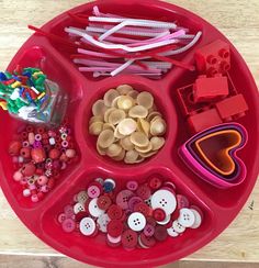 a red tray filled with lots of different types of buttons and other things on it