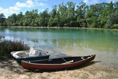 two small boats sitting on the shore of a lake