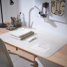 a white desk topped with a laptop computer next to a pile of papers and pens