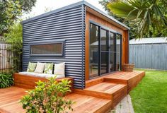 a small house made out of shipping containers with sliding glass doors on the front and side