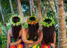 three women in colorful dresses standing next to each other on the beach with palm trees behind them