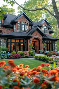 a beautiful house with lots of flowers in the front yard and landscaping around it is surrounded by greenery