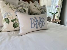 two pillows on top of a white bed with blue and green floral print pillow cases