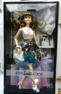 a barbie doll in a box with clothes and accessories on it's display stand