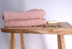 a wooden table topped with two pink blankets and a soap bar on top of it