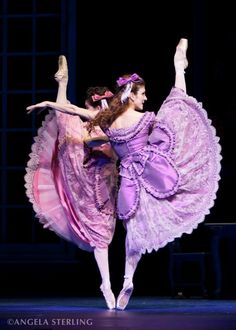 two ballerinas in purple dresses are performing on stage