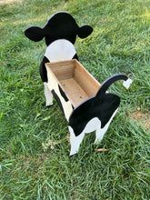 a toy cow that is in the grass