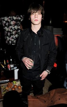 a young man standing next to a table full of food and drinks