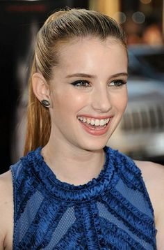 a woman with long hair smiling and wearing blue dress on the red carpet at an event