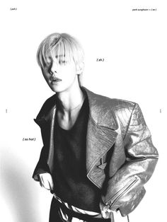 a black and white photo of a woman with blonde hair wearing a leather jacket, standing in front of a wall