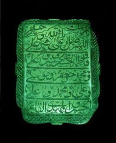 a green glass plaque with arabic writing on it's sides and an inscription in the middle