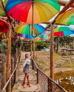 a woman standing on a wooden walkway under colorful umbrellas