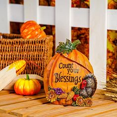 a carved pumpkin sitting on top of a wooden table next to corn and other autumn decorations