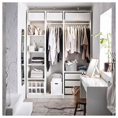 a white closet filled with lots of clothes next to a desk and chair in front of a window