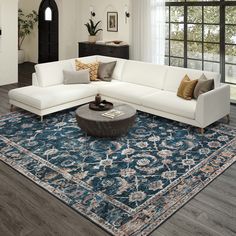 a living room with a large blue rug on the floor and a white sectional couch