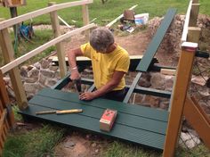 an older man sitting on a bench with tools in his hand and working on something