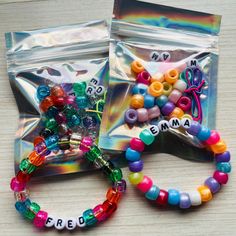 two bracelets with letters on them sitting next to a bag of beaded charms