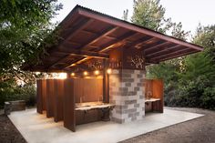 an outdoor hot tub in the middle of a wooded area with lights hanging from it's roof